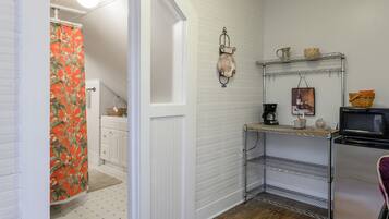 A compact kitchen with white cabinetry, a microwave, and a small refrigerator.
