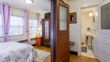 A bedroom with a bed, dresser, and a bathroom with a sink and mirror.