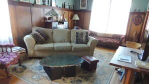 Una sala de estar con un sofá, una mesa de centro, un tapete estampado y un mueble de madera.