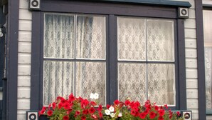 Un edificio con una ventana que tiene un balcón con flores rojas y blancas.