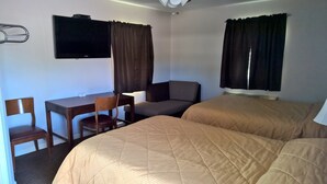 Une chambre d’hôtel avec deux lits, un bureau, une chaise, une télévision et des rideaux.