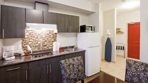 A compact kitchen with dark cabinets, a microwave, and a coffee maker. - Travelodge by Wyndham Kindersley (Kindersley)