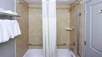A bathroom with a shower, a bathtub, and a handrail.