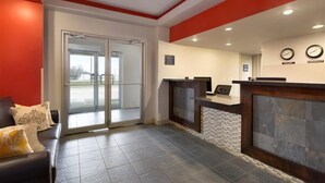 A reception area with a glass door entrance, a reception desk, and a clock on the wall. - Travelodge by Wyndham Kindersley (Kindersley)
