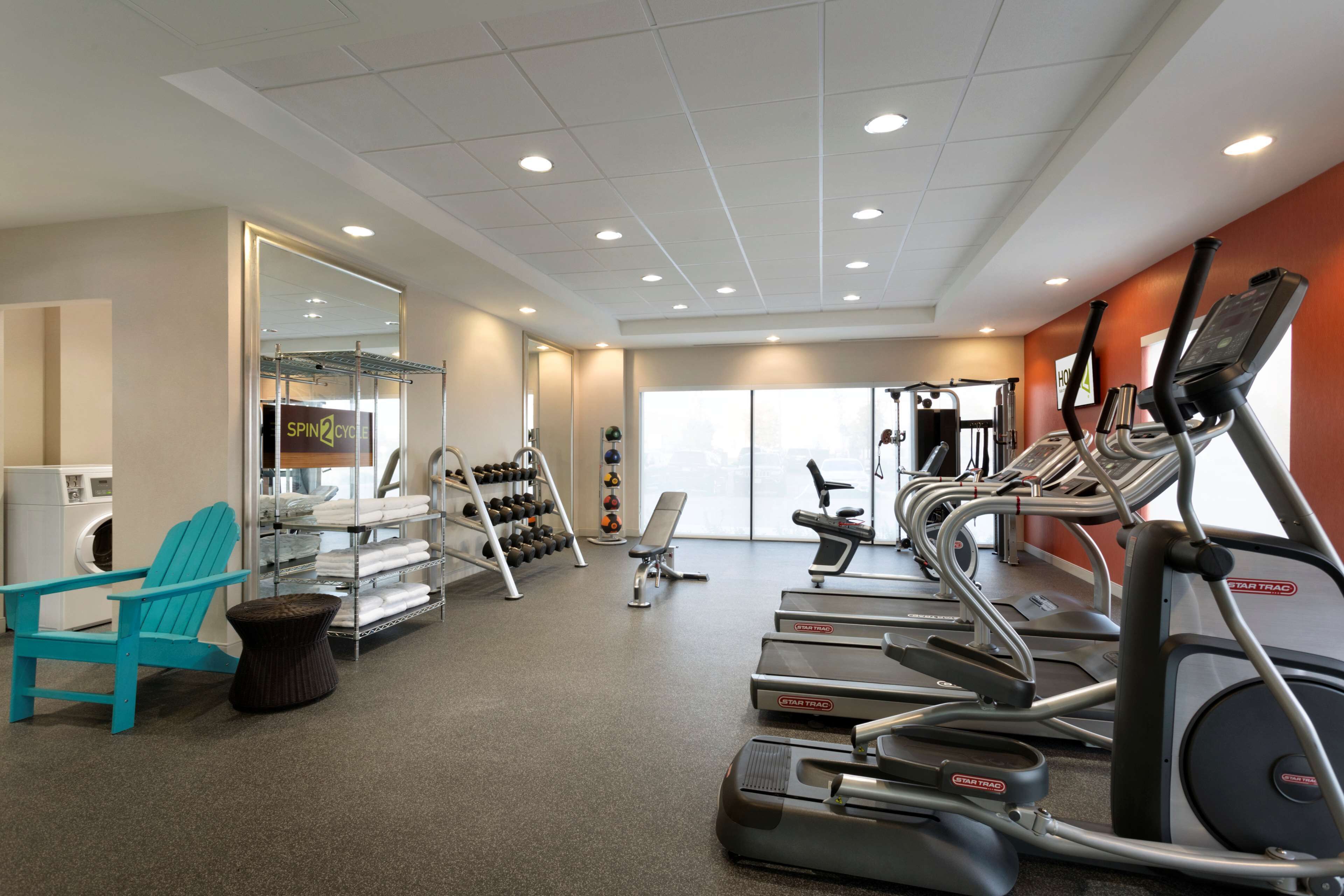 A gym with treadmills, a chair, a bench, and a rack of dumbbells.