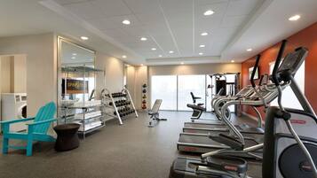 A gym with treadmills, a chair, a bench, and a rack of dumbbells.