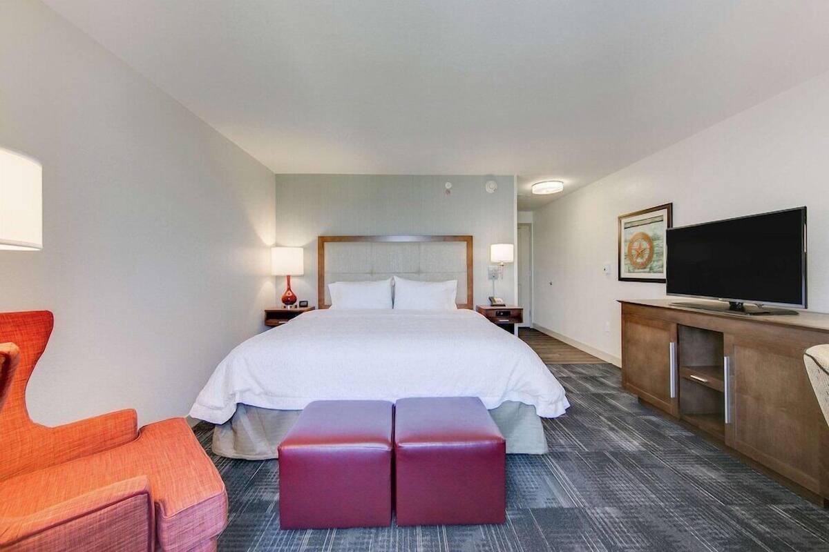 A hotel room with a large bed, a television, a desk with a computer, and a chair.