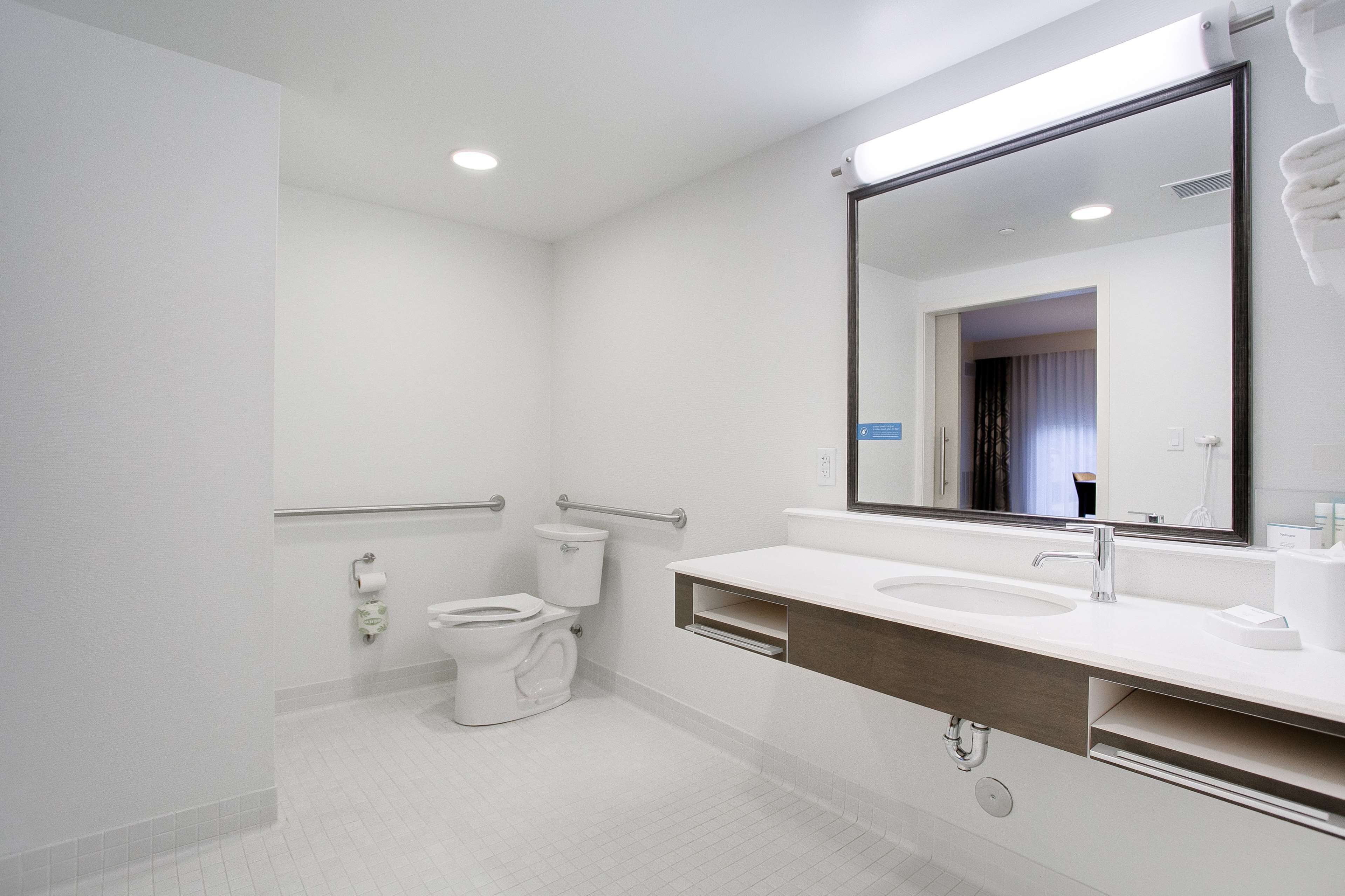 A modern bathroom with a white sink, mirror, and toilet.