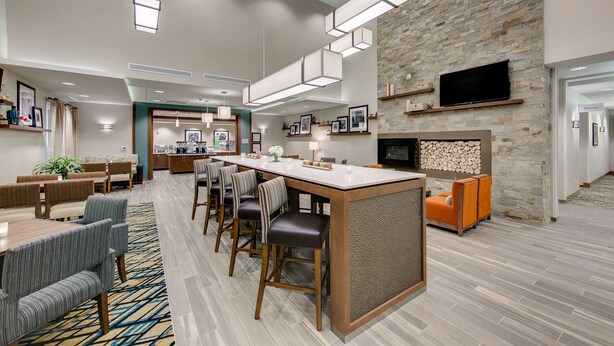 Un moderno vestíbulo de hotel con una barra central, zona de comedor y una pared de acento de piedra.