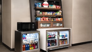 A vending machine with snacks and a microwave, and two refrigerated beverage dispensers. - Hampton Inn Fairmont (Fairmont)