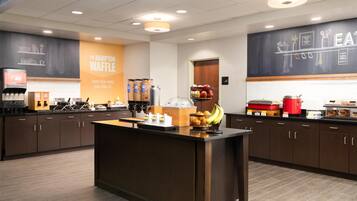 A modern kitchen area with a central island, a coffee machine, and a variety of food items on the counter.