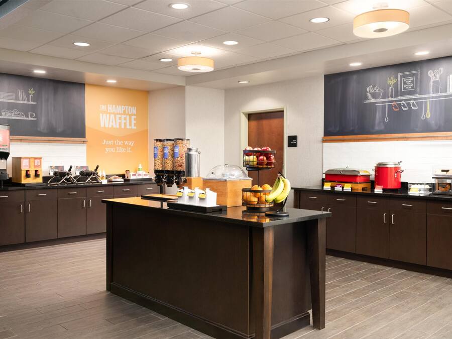 A modern kitchen area with a central island, a coffee machine, and a variety of food items on the counter.