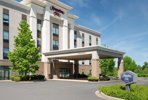 Un hotel Hampton Inn con entrada despejada, un letrero que indica una altura libre de 3.8 metros y un cartel de bienvenida.