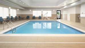 A swimming pool with blue tiles, surrounded by lounge chairs and a tiled floor. - Hampton Inn Fairmont (Fairmont)