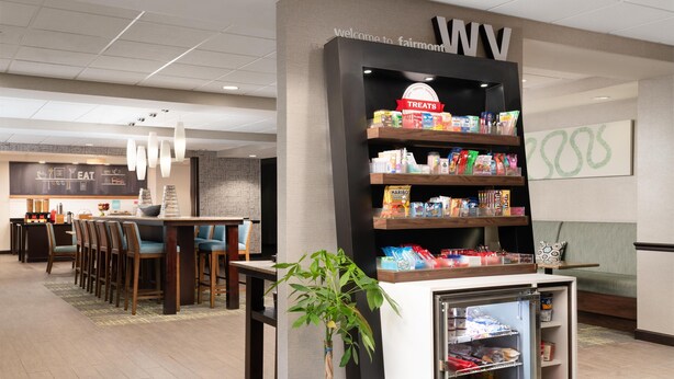 A hotel lobby with a reception desk, seating area, and a snack bar. - Hampton Inn Fairmont (Fairmont)