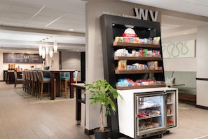 Un bar d’hôtel proposant des collations, avec un présentoir réfrigéré et un espace pour s’asseoir.