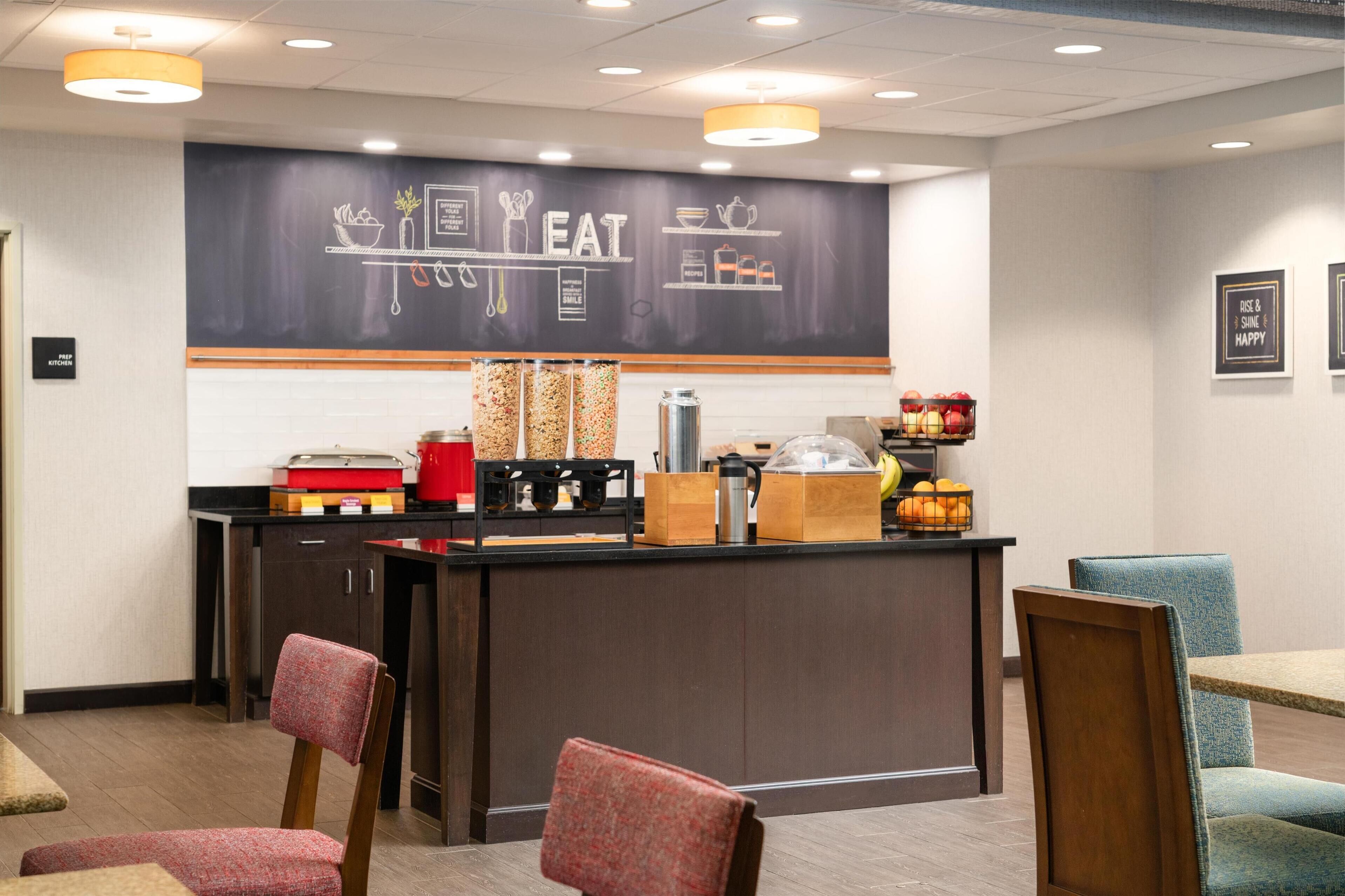 A restaurant counter with a chalkboard menu, various food items, and seating arrangements.