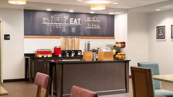 A restaurant counter with a chalkboard menu, various food items, and seating arrangements.