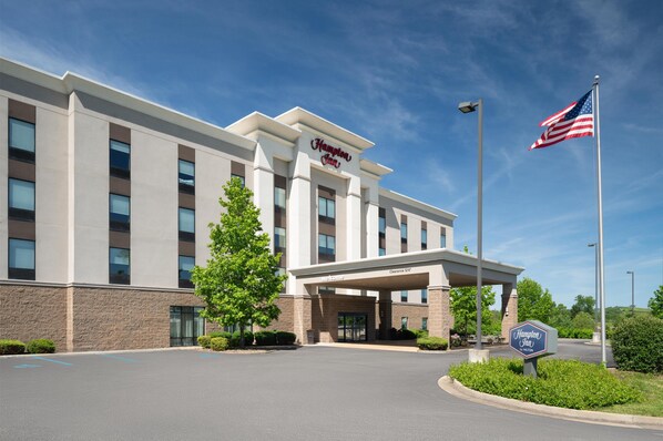 A Hampton Inn hotel with a clear sky, an American flag, and a sign indicating a 1250 clearance.