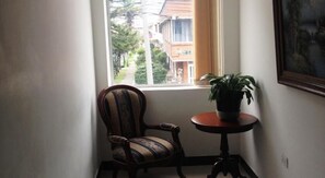 Ein Eckzimmer mit Fenster, einem Sessel und einem Tisch mit Blumentopf.