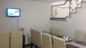 A conference room with a table, chairs, and a flat-screen TV mounted on the wall. - Hotel Casa La Embajada Colonial (Bogotá)