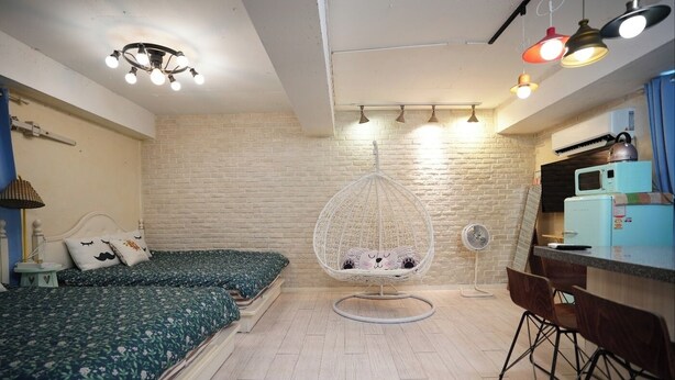 A compact room with a bed, a hanging chair, a small kitchenette, and a fan. - Residence Unicorn in Dongdaemun (Seoul)