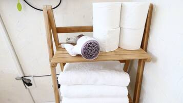 A wooden shelf with a hairdryer and rolled towels.
