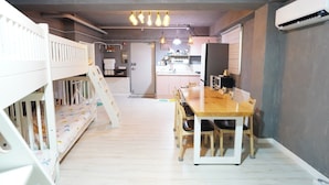 A room with a bunk bed, a dining table with chairs, a kitchen area, and an air conditioning unit. - Residence Unicorn in Dongdaemun (Seoul)