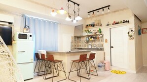 A compact kitchen with a refrigerator, microwave, and bar stools. - Residence Unicorn in Dongdaemun (Seoul)