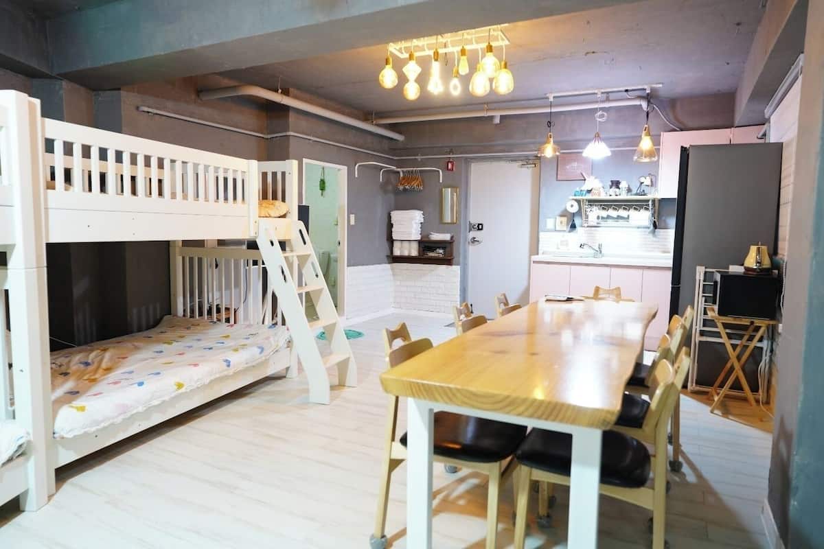 A room with bunk beds, a dining table, and a kitchen area.