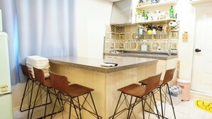 A kitchen with a bar area, two stools, and a refrigerator. - Residence Unicorn in Dongdaemun (Seoul)