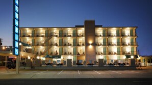 A multi-story hotel with a prominent neon sign, multiple balconies, and a central staircase. - Aquarius Oceanfront Inn (Wildwood)