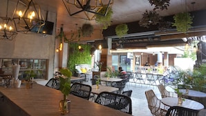 An indoor dining area with hexagonal hanging lights, black wicker chairs, and tables. - Gemini Star Hotel Kuta (Kuta)