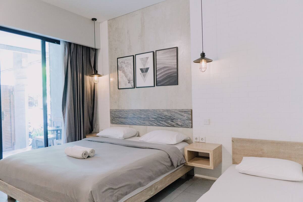 A modern hotel room with a large bed, a nightstand, and a view of the city.