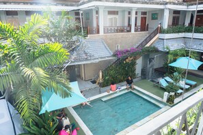 A pool area with a view of the surrounding buildings, a staircase, and some greenery. - Gemini Star Hotel Kuta (Kuta)