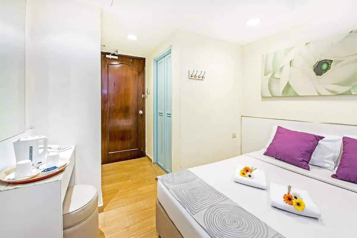 Quarto de hotel com cama, banheiro e corredor.