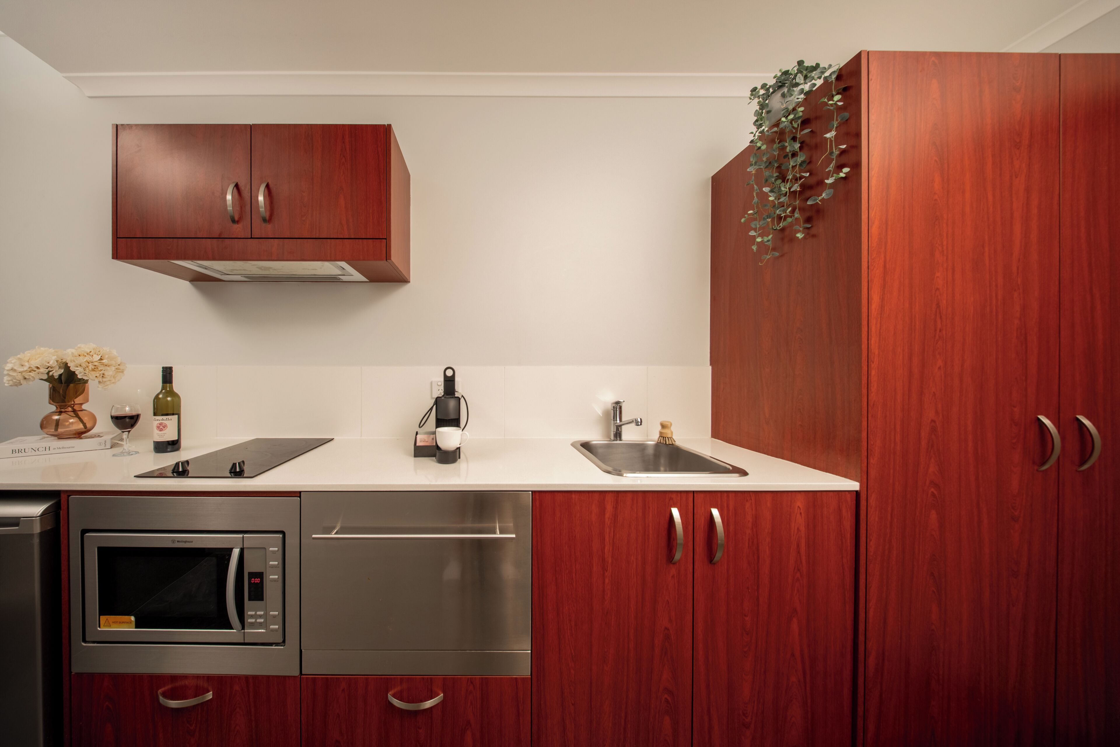 A modern kitchen with wooden cabinets, a built-in microwave, a sink, and a coffee maker.