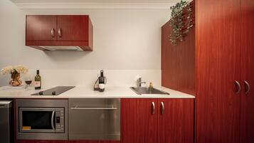 A modern kitchen with wooden cabinets, a built-in microwave, a sink, and a coffee maker.