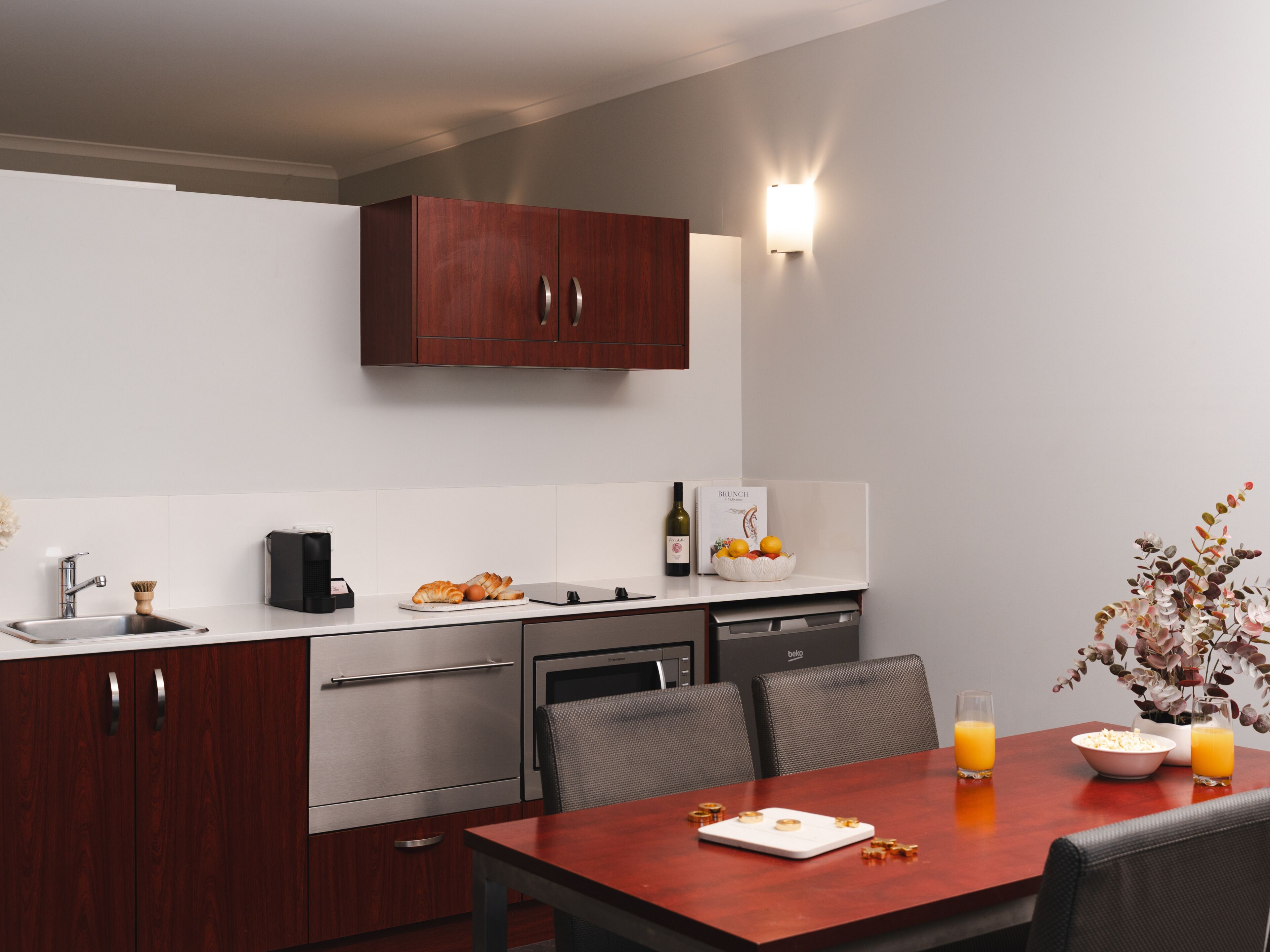 A modern kitchen with a dining area, including a wooden table, chairs, and a white countertop.