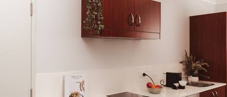 A modern kitchen with a white countertop, a built-in oven, and wooden cabinets.