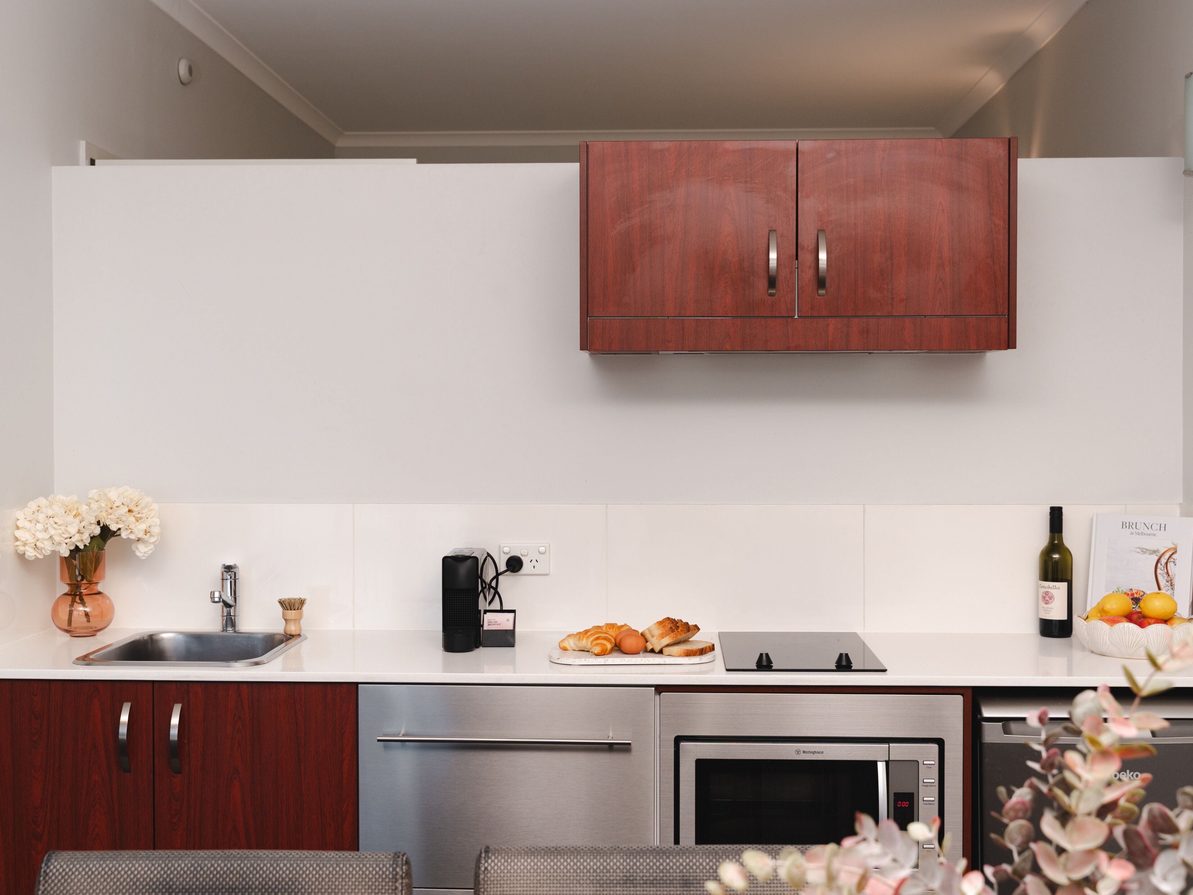 A modern kitchen with wooden cabinets, stainless steel appliances, and a white countertop.