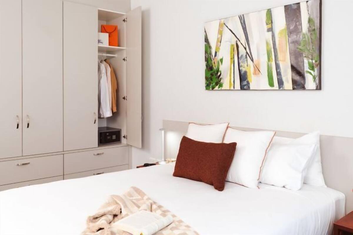 Un dormitorio con cama, armario y un cuadro en la pared.