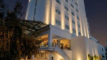 A modern hotel with a prominent sign, a staircase leading to the entrance, and a well-lit facade.