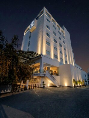 Ein modernes Hotel mit auffälliger Beschilderung, einer Treppe, die zum Eingang führt, und einer gut beleuchteten Fassade.