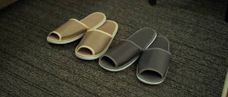 A pair of beige and gray slippers on a textured carpet.