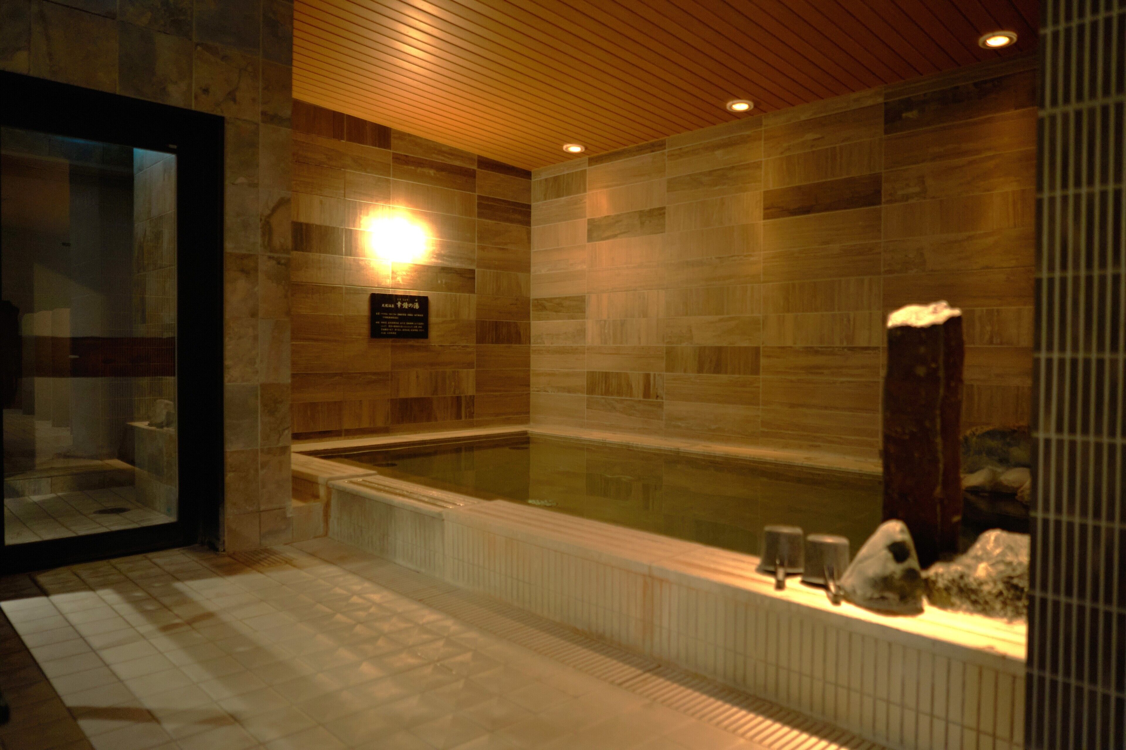 A modern bathroom with a large bathtub, wooden paneling, and a glass enclosure.