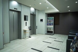 Un área de ascensores moderna con una mesa de recepción y un cartel en la pared.