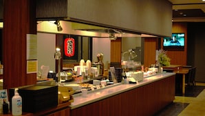 Een restauranttoonbank met diverse gerechten, een televisiescherm en een houten inrichting.