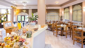 A buffet area with various food items and a seating area with wooden chairs and tables. - Eltina Hotel (Rethymno)