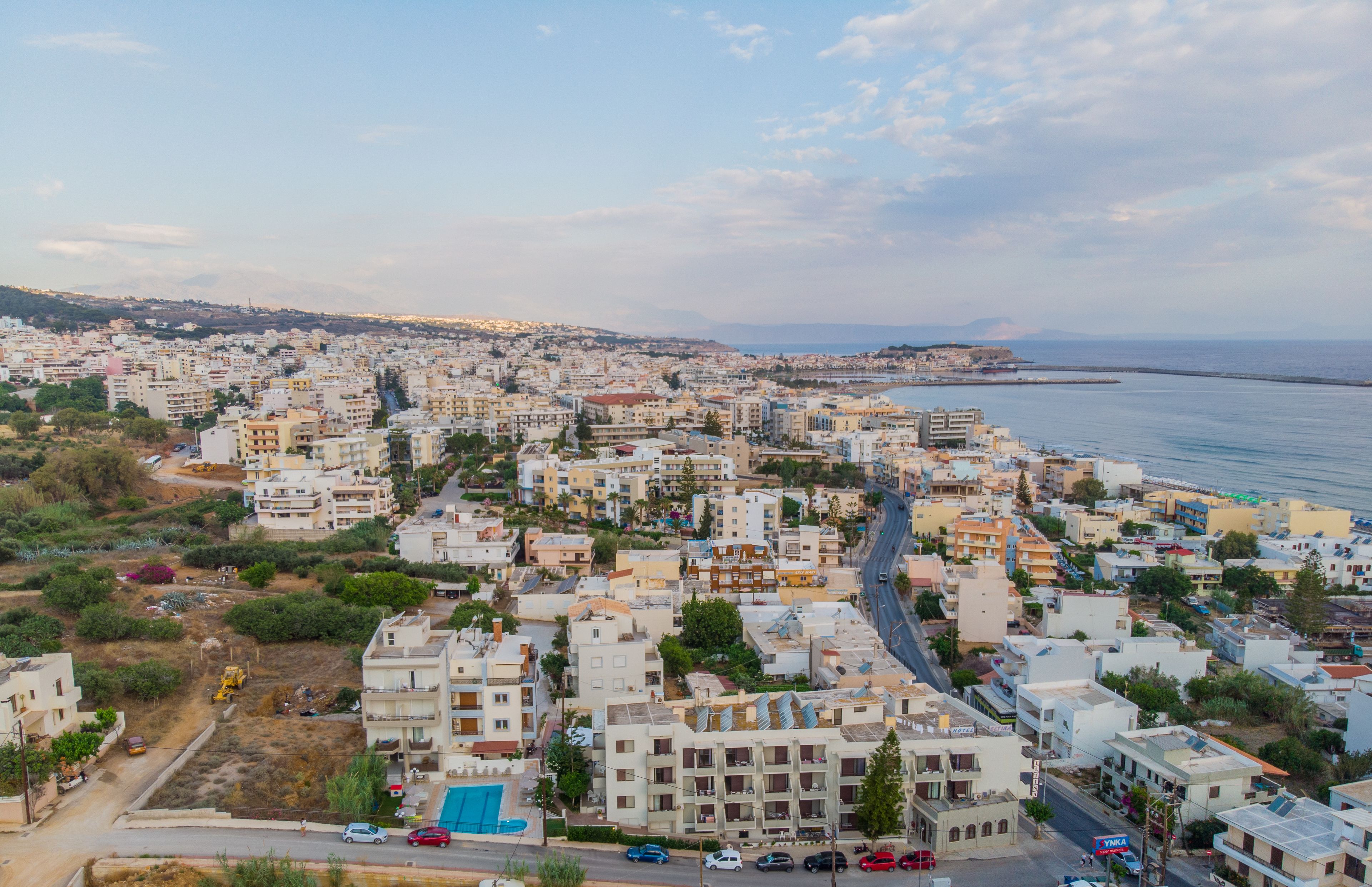 Un paysage urbain côtier caractérisé par une forte densité de constructions, une route bien visible et une étendue d’eau en arrière-plan.